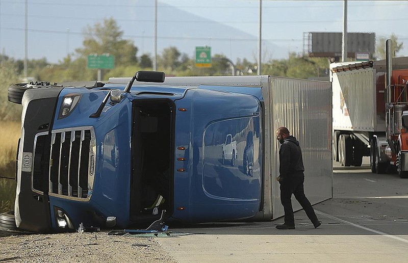 A tractor-trailer rig rests on its side Tuesday after being toppled by high winds on Interstate 15 in salt Lake City. (ap/the deseret news/Jeffrey d. allred) 