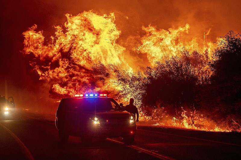 Flames lick above vehicles on Highway 162 as the Bear Fire burns in Oroville, Calif., on Wednesday, Sept. 9, 2020. The blaze, part of the lightning-sparked North Complex, expanded at a critical rate of spread as winds buffeted the region.
story.lead_photo.caption
