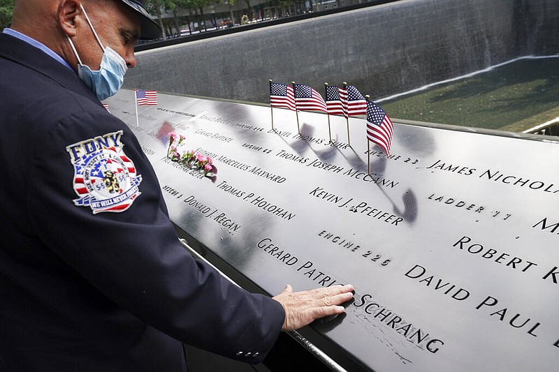 A mourner brushes water with his fingers over the name cut-outs of the deceased at the National September 11 Memorial and Museum, Friday, Sept. 11, 2020, in New York. 