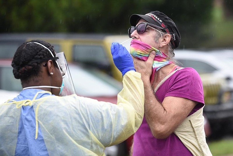 Natasha Cleveland, a health worker with the University of Arkansas for Medical Sciences Northwest Regional Campus, conducts a coronavirus test Sept. 10, 2020 on Bobby Morell during a drive-thru clinic on the campus in Fayetteville. (NWA Democrat-Gazette/David Gottschalk)