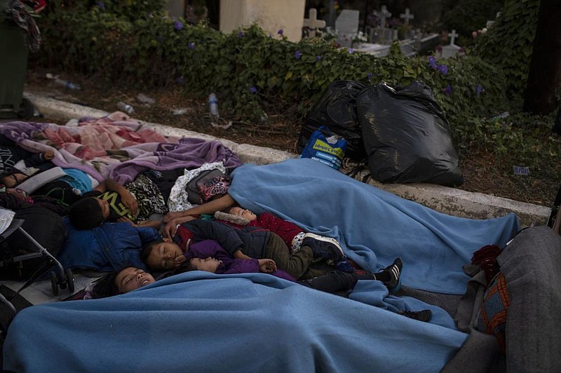 Migrants sleep Thursday on the road near the Moria refugee camp on the Greek island of Lesbos after fires gutted the structures where they had been sheltered. More photos at arkansasonline.com/911lesbos/
(AP/Petros Giannakouris)