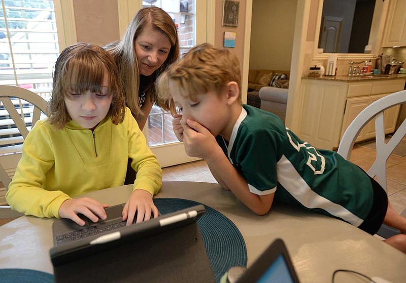 Katie Presley, 11, completes a school lesson on her laptop Thursday as her mother, Jacqueline Presley, and brother, Jackson, 9, watch her work at their dining room table in their home in Springdale. Both children are enrolled in the Springdale School District’s Virtual Innovation Academy in the Don Tyson School of Innovation. More photos at arkansasonline.com/913education/.
(NWA Democrat-Gazette/Andy Shupe)