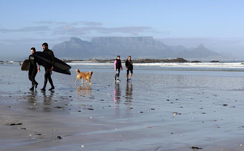 People walk on a beach, with Table Mountain in the background, in Cape Town, South Africa, in mid-August. (AP/Nardus Engelbrecht) 