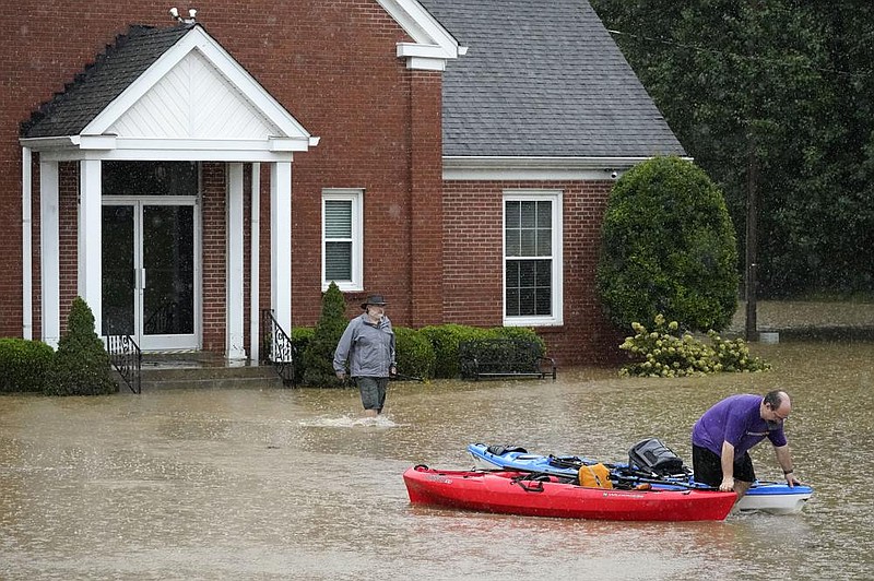 Phillip Brackett (right) a deacon at Mill Creek Church of Christ in Nolensville, Tenn., pulls two kayaks through the parking lot after a flash flood Sunday put several inches of water inside the church. At left is preacher Nick Fowler. 
(AP/Mark Humphrey) 