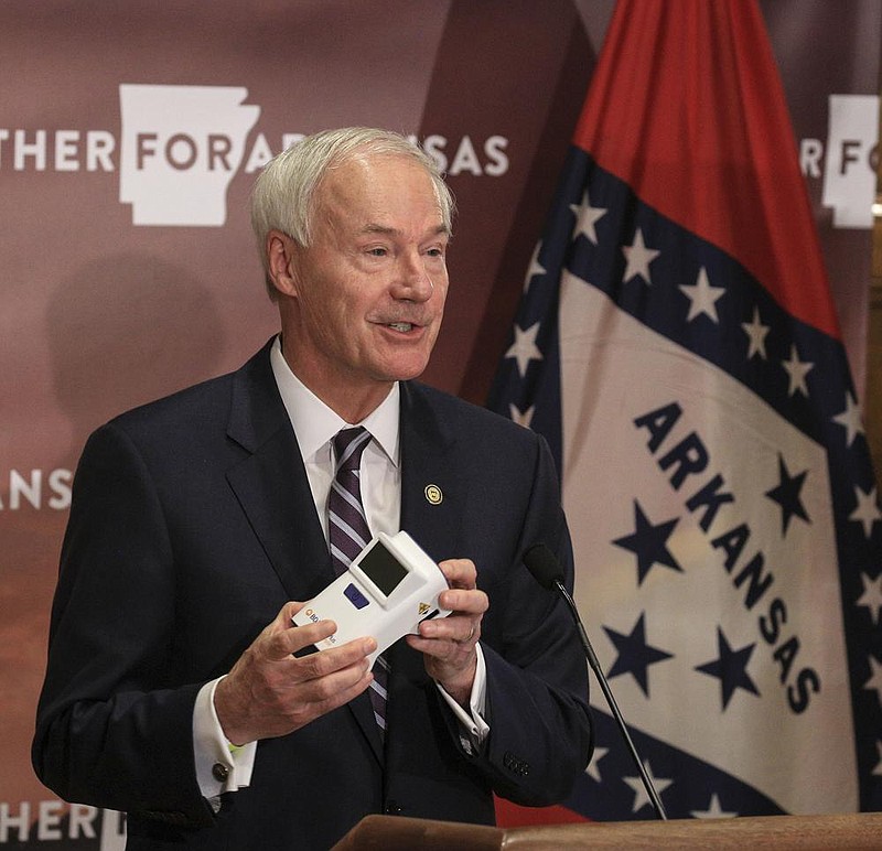 Gov. Asa Hutchinson holds an antigen testing machine Tuesday Sept. 15 in Little Rock as he speaks during a COVID-19 briefing at the state Capitol. (Arkansas Democrat-Gazette/Staton Breidenthal) story.lead_photo.caption
