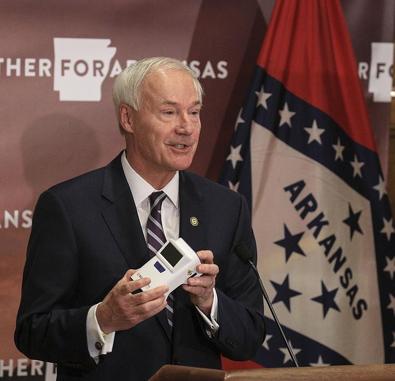 Gov. Asa Hutchinson holds an antigen testing machine Tuesday Sept. 15 in Little Rock as he speaks during a COVID-19 briefing at the state Capitol. (Arkansas Democrat-Gazette/Staton Breidenthal)