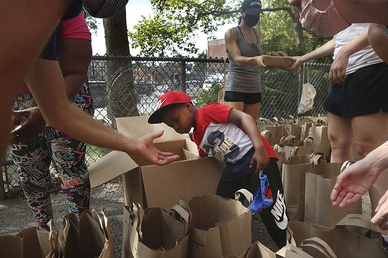 Hunter Stewart, 5, helps pack and deliver food to residents of the Lafayette Gardens housing development on Hunter Stewart, 5, helps pack and deliver food to residents of the Lafayette Gardens housing de- velopment in New York’s Brooklyn borough last month. After Hunter and his family struggled to put food on the table in the first months of the pandemic, they volunteered to help distribute supplies to neighbors who also were having difficulty staving off hunger. 
(AP/Jessie Wardarski) 