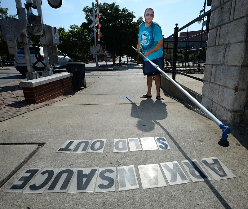 Jarrod Hunt picks up letters from the sidewalk Aug. 6 as he changes the marquee outside George’s Majestic Lounge on Dickson Street in Fayetteville, just before the venue’s first live performance held after closing because of the pandemic. The City Council approved leasing land to the south for an outdoor stage.

(File photo/NWA Democrat-Gazette/Andy Shupe)