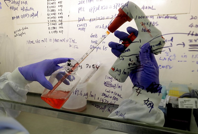 FILE - In this July 30, 2020 photo, Kai Hu, a research associate transfers medium to cells, in the laboratory at Imperial College in London. Imperial College is working on the development of a covid-19 vaccine.
