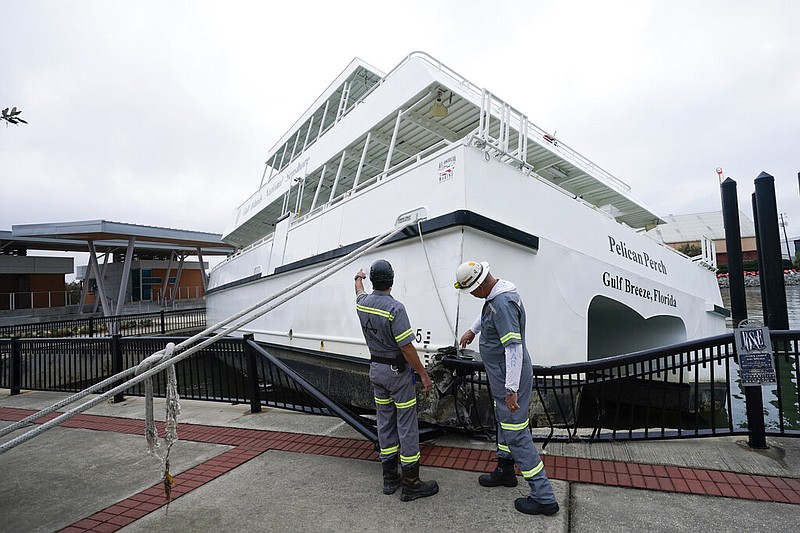 Workers look over a damaged ferry , Thursday, Sept. 17, 2020, in Pensacola, Fla. Rivers swollen by Hurricane Sally's rains threatened more misery for parts of the Florida Panhandle and south Alabama on Thursday, as the storm's remnants continued to dump heavy rains inland that spread the threat of flooding to Georgia and the Carolinas.(AP Photo/Gerald Herbert)

