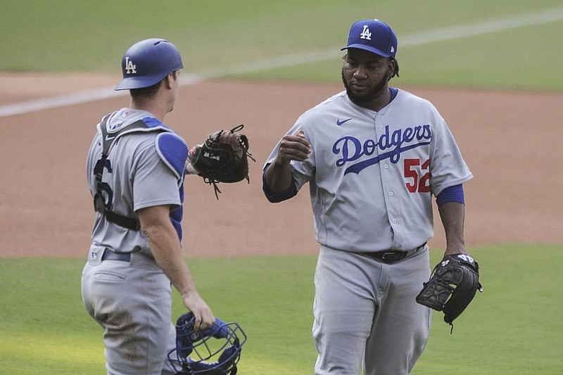 Los Angeles Dodgers relief pitcher Pedro Baez (right) is congratulated by catcher Will Smith after the Dodgers’ 7-5 victory over the San Diego Padres on Wednesday. With the victory, the Dodgers became the first team to clinch a berth in the expanded playoffs. 
(AP/Derrick Tuskan)