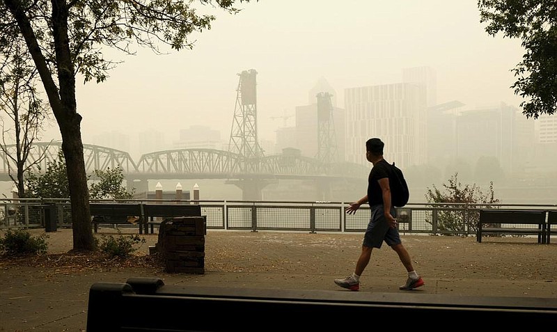 A man walks near the Willamette Bridge in downtown Portland, Ore., on Wednesday as smoke from wildfires continues to cloud the area. More photos at arkansasonline.com/917fires/.
(AP/Don Ryan)