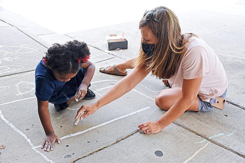 Becky Caldwell, a staff member of Scholastic Academy Pre-School, makes chalk drawings with student Ja’Mea on Thursday, Sept. 17, 2020, in front of the preschool in Little Rock. (Arkansas Democrat-Gazette/Staci Vandagriff)