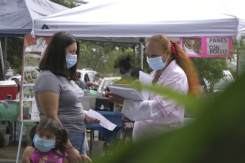 A "promotora" (health promoter) from CASA, a Hispanic advocacy group, tries to enroll Latinos as volunteers to test a potential COVID-19 vaccine, at a farmers market in Takoma Park, Md., on Sept. 9, 2020. Minority enrollment in studies of two shots has inched up in recent weeks, but even more is needed this fall as additional vaccine testing gets underway over the next two months. (AP Photo/Federica Narancio)

