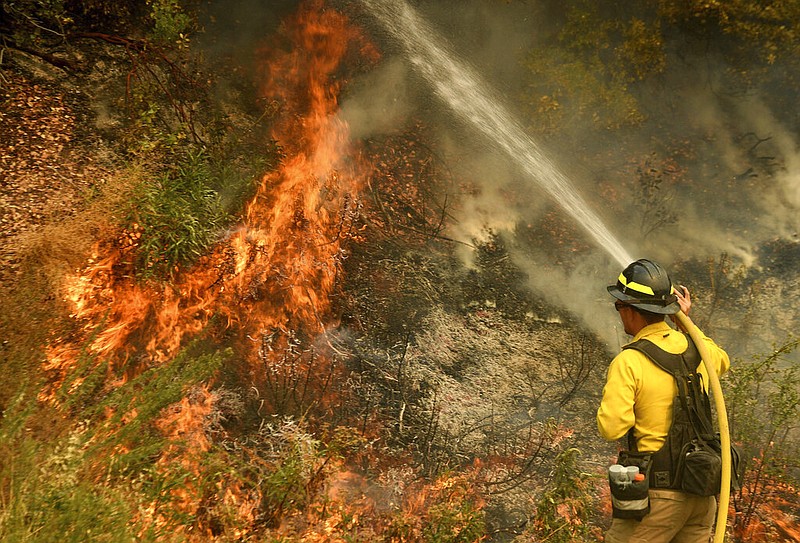 A firefighter puts out a hot spot along Highway 38 northwest of Forrest Falls, Calif., as the El Dorado Fire continues to burn Thursday afternoon, Sept. 10, 2020.