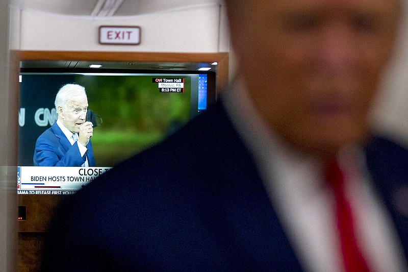 A television screen shows Democratic presidential candidate former Vice President Joe Biden holding up a mask, as President Donald Trump talks with reporters on Air Force One while returning to Washington after a campaign rally at Central Wisconsin Airport, Thursday, Sept. 17, 2020.
