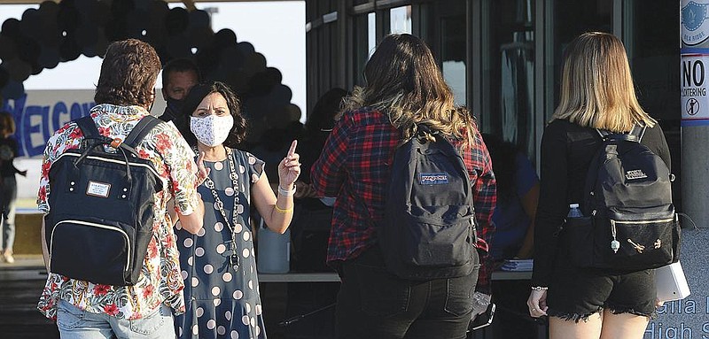 Virginia Legros, director of Guidance at Gila Ridge High School in Yuma, Ariz., explains the guidelines Thursday while greeting students arriving for the first day of on-campus instruction for students with last names M-through-Z.
(AP/The Yuma Sun/Randy Hoeft)