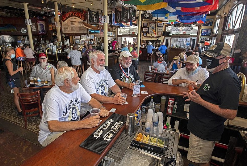 Charlie Boice (center, in dark shirt) and fellow Hemingway lookalikes Dusty Rhodes (from left) and Tim Stockwell chat with bartender Lou Gammel at Thursday’s reopening of Sloppy Joe’s in Key West, Fla.
(AP/Florida Keys News Bureau/Rob O’Neal)