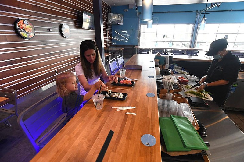 Kelsey Webster of Bentonville eats sushi with her daughter Natalie on Wednesday at the Hissho Sushi and Craft Beer Bar located in the Walmart store at Pleasant Crossing Boulevard in Rogers. (NWA Democrat-Gazette/J.T.WAMPLER)