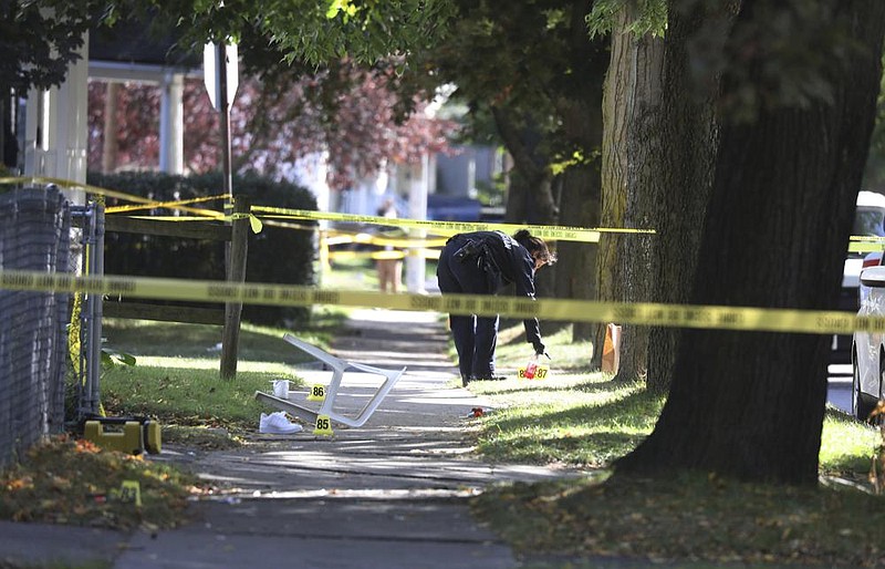 A police technician collects evidence near the home where a house party turned deadly early Saturday in Rochester, N.Y. (AP/Democrat & Chronicle/Tina MacIntyre-Yee) 