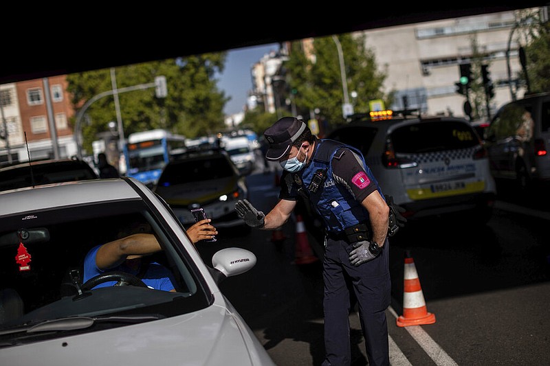 A local police stops a vehicle at a checkpoint in Madrid, Spain, Monday, Sept. 21, 2020. Police in the Spanish capital and its surrounding towns are stopping people coming in and out of working-class neighborhoods that have been partially locked down to stem Europe's fastest coronavirus spread. (AP Photo/Bernat Armangue) story.lead_photo.caption