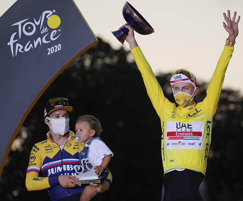 Tadej Pogacar of Slovenia holds the trophy after winning the Tour de France on Sunday. Standing next to Pogacar is fellow country- man Primoz Roglic who held the lead late in the race. (AP/Christophe Ena)