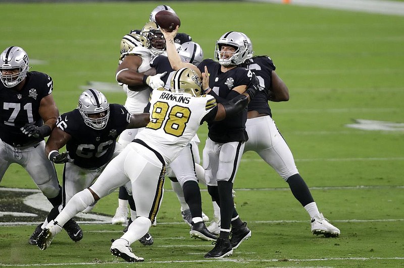 Las Vegas Raiders quarterback Derek Carr (right) passes over New Orleans Saints defensive tackle Sheldon Rankins (98) during the first half Monday in Las Vegas. Carr threw for 282 yards and 3 touchdowns in a 34-24 victory for the Raiders. 
(AP/Isaac Brekken) 
