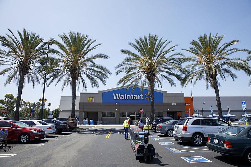 Shoppers wearing protective masks leave a Walmart store in Lakewood, Calif., in this July file photo. Walmart said Monday that it is targeting zero emissions from its global operations by 2040. (Bloomberg News/Patrick T. Fallon) 