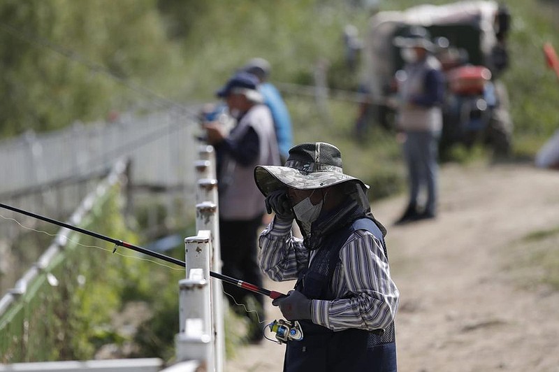 People keep a virus-safe distance Monday as they fish along a river in Seoul, South Korea. (AP/Lee Jin-man) 