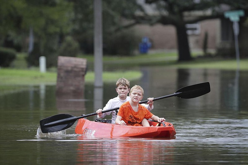 Josey Chambers, 11, and his brother sawyer, 7, make their way on a kayak up Wandering trail after Clear Creek in Friendswood, texas, over owed tuesday from rain from tropical storm beta. more photos at arkansasonline.com/923storm/. 
(ap/Houston Chronicle/steve Gonzales) 