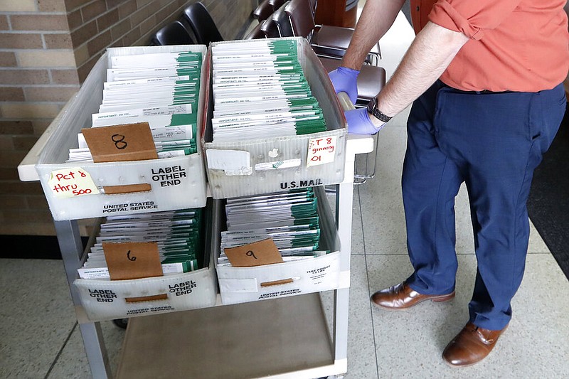 FILE - In this May 5, 2020, file photo, absentee ballots to be counted are moved at City Hall in Garden City, Mich. Data obtained by The Associated Press shows Postal Service districts across the nation are missing the agency’s own standards for on-time delivery as millions of Americans prepare to vote by mail.