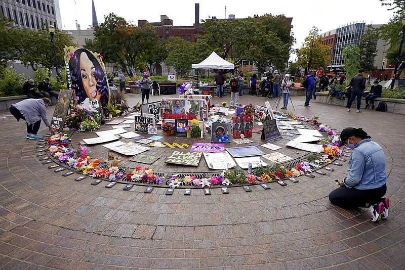 A women kneels in front of a makeshift memorial in honor of Breonna Taylor, at Jefferson Square Park, Thursday, Sept. 24, 2020, in Louisville, Ky.