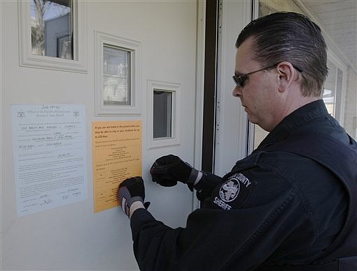 A sheriff's deputy posts a final eviction notice on an apartment in this 2009 file photo.
