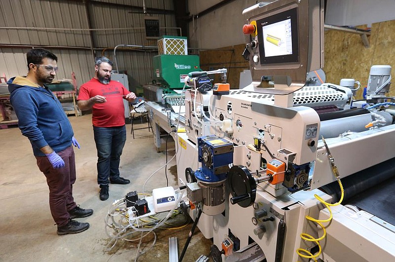 Hulusi Turgut (left), research chemical engineer with WattGlass, and Nathan Burford, research engineer, check the aesthetics of a coated piece of glass at the WattGlass warehouse in Fayetteville in this December file photo.
(NWA Democrat-Gazette/David Gottschalk)