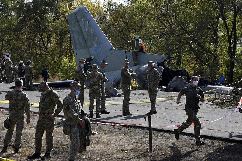 Ukrainian soldiers stand Saturday near where an AN-26 mili- tary plane crashed in Ukraine. More photos at arkansasonline. com/927ukraine/. (AP/Andriy Andriyenko) 