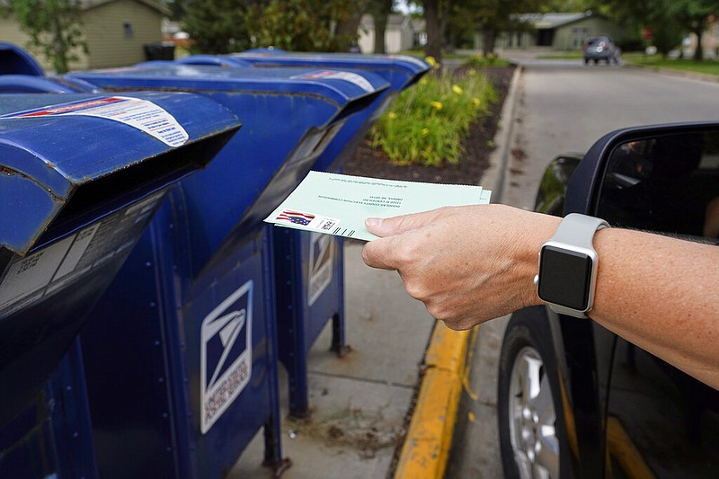 FILE - In this Tuesday, Aug. 18, 2020, file photo, a person drops applications for mail-in-ballots into a mailbox in Omaha, Neb. Data obtained by The Associated Press shows Postal Service districts across the nation are missing the agency’s own standards for on-time delivery as millions of Americans prepare to vote by mail. (AP Photo/Nati Harnik, File)

