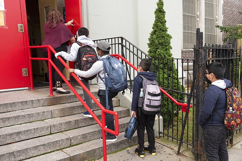 A teacher leads her students into an elementary school in the Brooklyn borough of New York on Tuesday, Sept. 29, 2020, as hundreds of thousands of elementary school students are heading back to classrooms in the city, resuming in-person learning during the coronavirus pandemic. The coronavirus is infecting a rising number of American children and teens in a trend authorities say appears driven by school reopenings and the resumption of sports, playdates and other activities. (AP Photo/Mark Lennihan)

