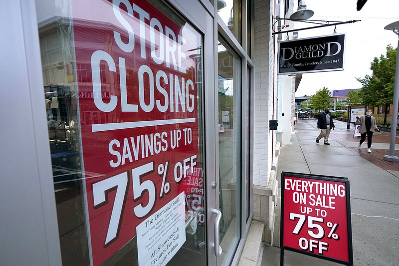 FILE - In this Sept. 2, 2020 file photo, pedestrians walk past a business storefront with store closing and sale signs in Dedham, Mass.