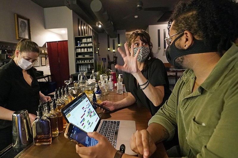 Mama Fox bar and restaurant owner Samantha DiStefano (center) discusses her indoor dining reopening plans with manager Akin Payne as bartender Devon Schickling prepares drinks for outdoor diners Tuesday in New York. The establishment was preparing to serve patrons indoors for the first time since March.
(AP/Kathy Willens)