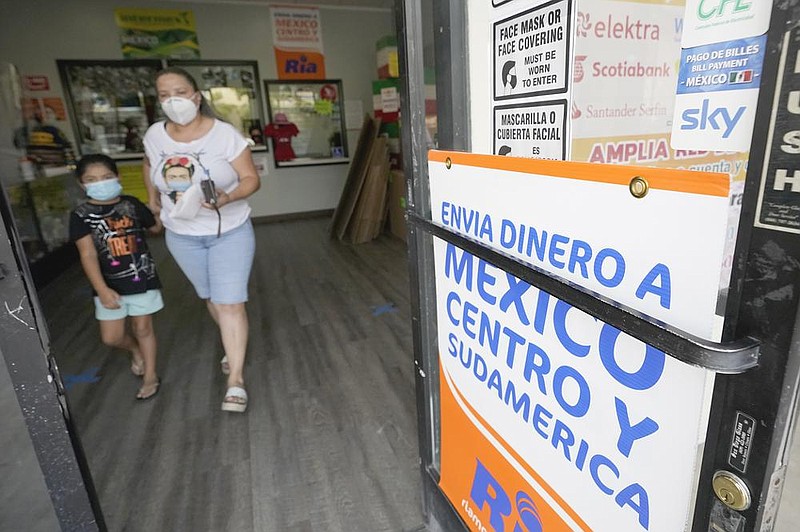 A woman exits a store in San Diego last month that offers services to send remittances to Mexico and Central America, which have continued to flow during the pandemic.
(AP)