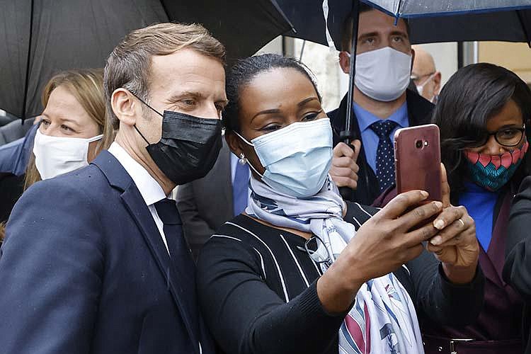 French President Emmanuel Macron poses for a selfie Friday with a resident during his visit to the town of Les Mureaux.
(AP/Ludovic Marin)