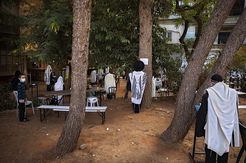 Ultra-Orthodox Jews in Bnei Brak, Israel, keep social distancing and wear face masks during a morning prayer next to their houses as synagogues are limited to 20 people due to the coronavirus pandemic.
(AP/Oded Balilty)