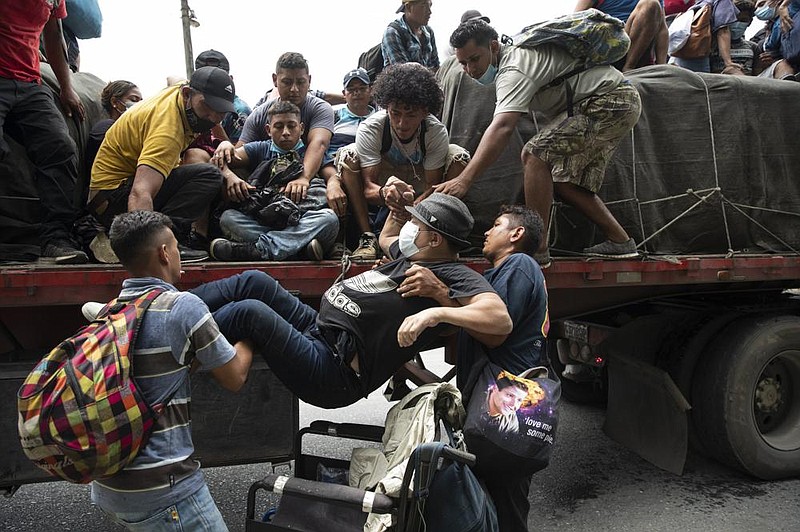A wheelchair-bound migrant is helped by fellow migrants onto the back of a freight truck giving the migrants a ride in Rio Dulce, Guatemala. More photos at arkansasonline.com/103migrants/.
(AP/Moises Castillo)