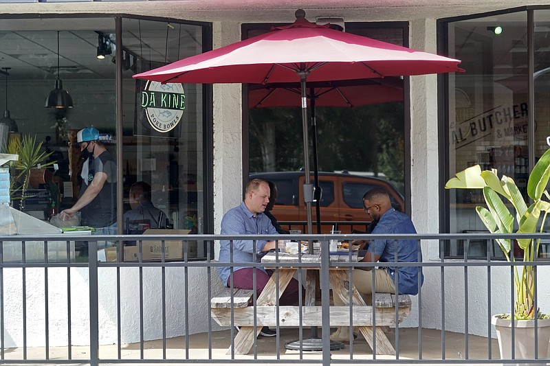 Patrons dine at a restaurant Friday, Oct. 2, 2020, in Winter Park, Fla. In his drive to return the state to normalcy, Republican Gov. Ron DeSantis lifted limits on indoor seating at restaurants, saying they can operate at 100% in municipalities with no restrictions and that other local governments can't restrict indoor seating by more than 50%. (AP Photo/John Raoux)