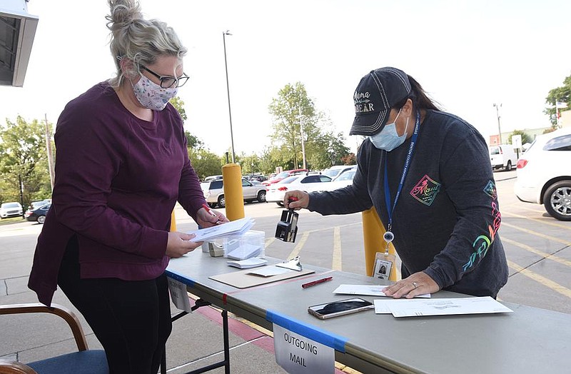 Courtney Leemasters (left) and Deanna Evans, both with the Benton County clerk’s office, work Saturday with absentee ballots that people turned in outside the county administration building in Bentonville. More photos at arkansasonline.com/104dropoff/.
(NWA Democrat-Gazette/Flip Putthoff)