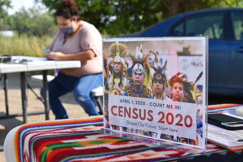 FILE - In this Aug. 26, 2020, file photo, a sign promoting Native American participation in the U.S. census is displayed as Selena Rides Horse enters information into her phone on behalf of a member of the Crow Indian Tribe in Lodge Grass, Montana. A complete count of Montana’s households could come with a big reward: a second seat in Congress and millions of federal dollars annually. But the 2020 census deadline remains in flux, making it uncertain if census takers will finish counting the vast, rural state. (AP Photo/Matthew Brown, File)

