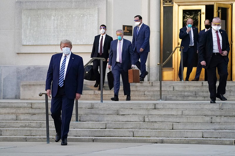 President Donald Trump, left, walks out of Walter Reed National Military Medical Center to return to the White House after receiving treatments for covid-19, Monday, Oct. 5, 2020, in Bethesda, Md. (AP Photo/Evan Vucci)