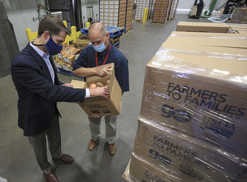 Sen. Tom Cotton, left, looks inside a Farmers to Families food box as he tours the Arkansas Foodbank Monday Oct. 5, 2020 in Little Rock with Foodbank Chief Operations Officer Eric Shelby. (Arkansas Democrat-Gazette/Staton Breidenthal)