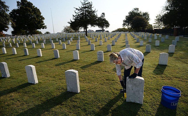 Gloria Taylor of Bella Vista cleans headstones Tuesday, Oct. 6, 2020, at the Fayetteville National Cemetery as she and other volunteers prepare the cemetery for Veterans Day as a part of the Honor and Respect Headstone Cleaning Project organized by Bo's Blessings and the Fayetteville National Cemetery. (NWA Democrat-Gazette/Andy Shupe)
