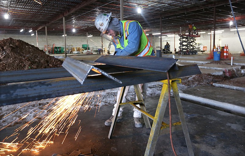 Tanner Myers with Nabholz Construction grinds the edge of angle iron for supports of roof top units Wednesday, Jan. 15, 2020, inside the new location of Ozark Natural Foods, 380 N. College Ave., in Fayetteville. The new store opened in June at the former site of an IGA and features an expanded farm and garden department, a taproom and coffee bar, an outdoor covered patio and to-go meals.